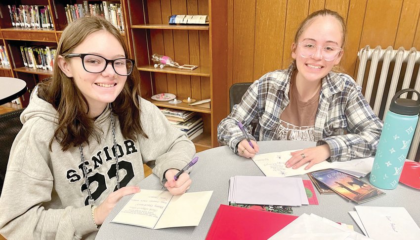 Juniors Devin Slusser, left, and Elsey Wuelling add some snowmen drawings to their holiday cards.