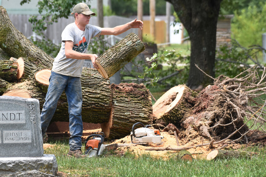 CALEB KRAMME removes tree limbs from the city cemetery on Monday.
