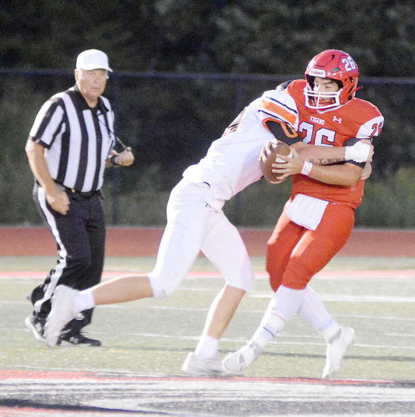 Dalton Pyrtle (left) wraps up St. James Tiger quarterback Cooper Harlan before bringing him down for a sack on fourth down during Owensville&rsquo;s 43-22 road victory Friday night in Phelps County.