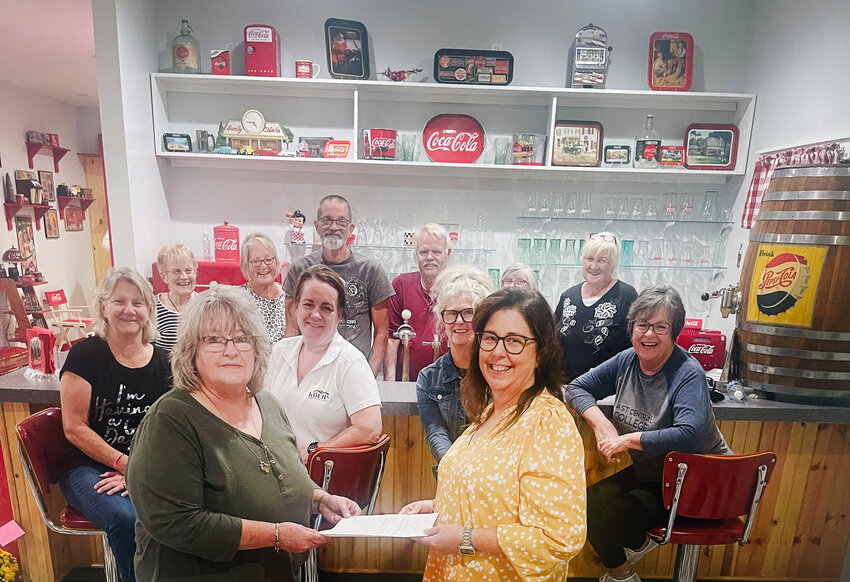 The Gerald Area Chamber of Commerce met in October in the shed of Otis and Jeanie Schulte. During the meeting the Chamber agreed to commit $1,000 toward the splash pad project the city is working on. In the foreground, Chamber President Marsha Adams is seen presenting a letter of commitment to Mayor Angela Koepke.
