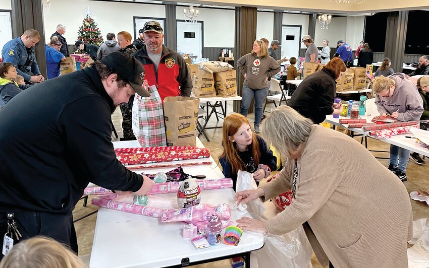 Kids from area schools paired up with members of law enforcement, EMS, and other agencies for Shop with a Hero on Saturday. They are shown here wrapping gifts at the Barefoot Event Center after buying gifts at Linn Thriftway and Dollar General.