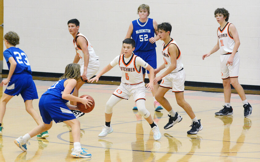 Brogan Clancy (center) gets in defensive position to guard Washington&rsquo;s Colton Burns during eighth-grade basketball action Monday night at Owensville Elementary School.