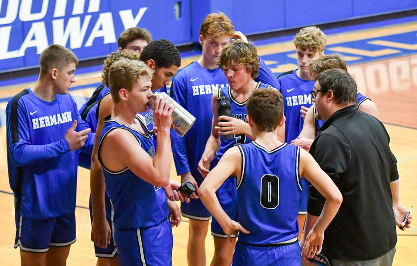 Hermann head basketball coach Jake Witthaus (far right) addresses his team during a timeout Friday night at South Callaway High School in Mokane.