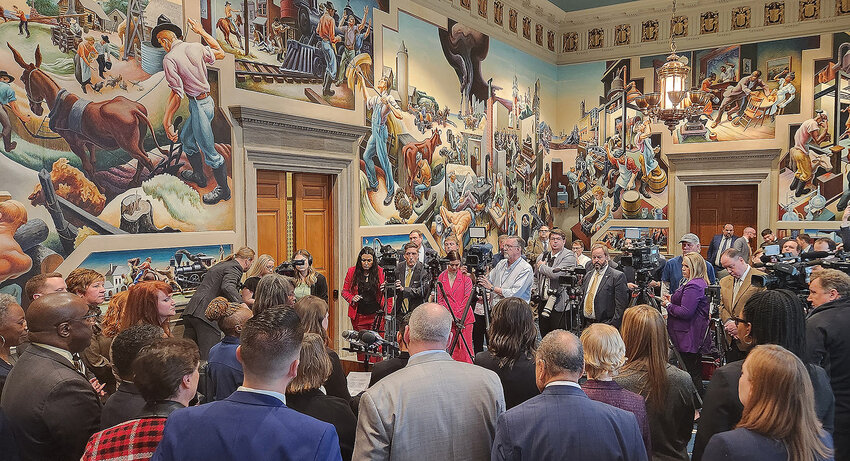 Missouri House of Representatives Democrats face members of the Capitol press and Missouri media members following the opening of the 2024 Legislative Session. Artwork by Thomas Hart Benton is painted on each wall of the House conference room on the third floor.