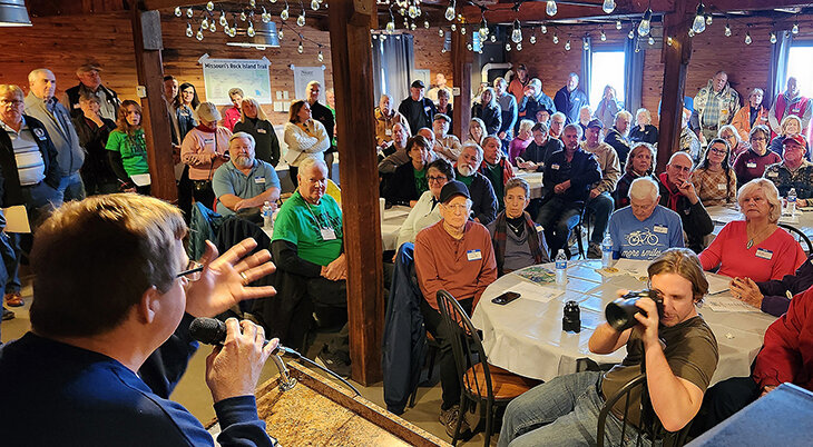 CARY PARKER welcomes about 150 people, including 40 Gerald Elementary students, to the indoor portion of the groundbreaking ceremony held upstairs at his Bistro at the Mill establishment. Among those attending were bicycle and trail enthusiasts from Rocheport and St. Peters, Mo., along with Missouri State Parks staff and administrators.