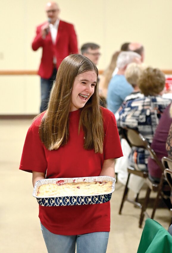 Callie Lock carries one of several desserts auctioned off at Lincoln Day to support the Catholic Youth of Osage County.
