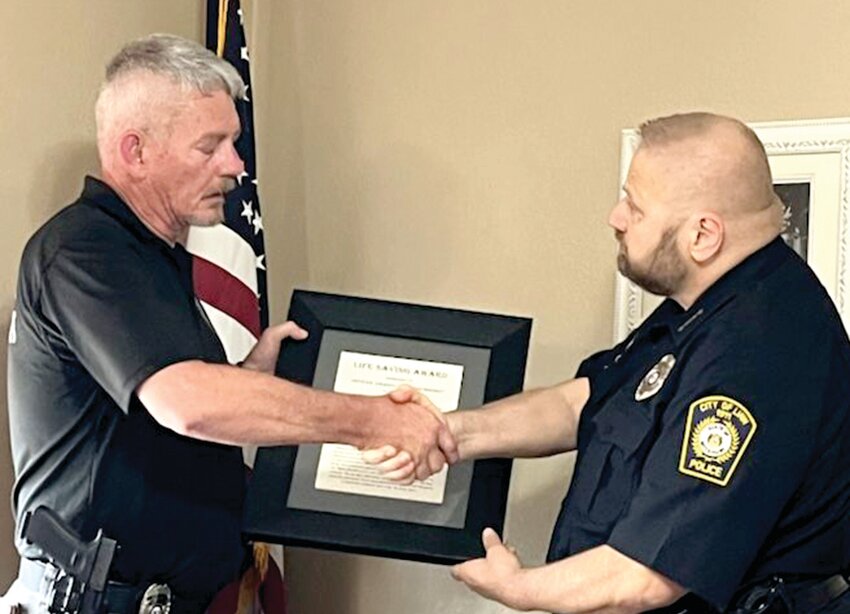 Linn Police Chief Sam Ford, right, presents Police Officer Darrell Chrisenberry the Life-Saving Award at last Tuesday‚ city meeting.