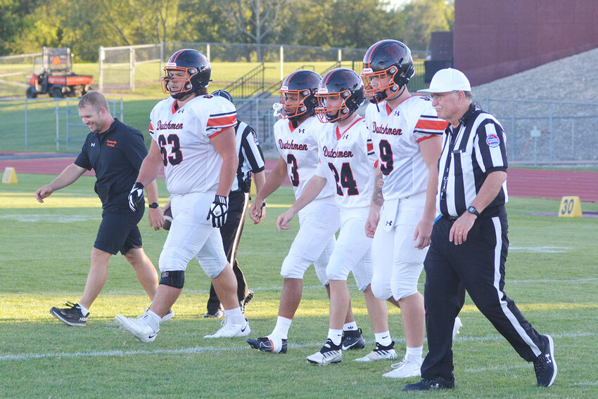 Hayden Shoemaker (second from left) walks to midfield as one of the Dutchmen football team captains during his senior season in road action at Victor Field against Eldon’s Mustangs.