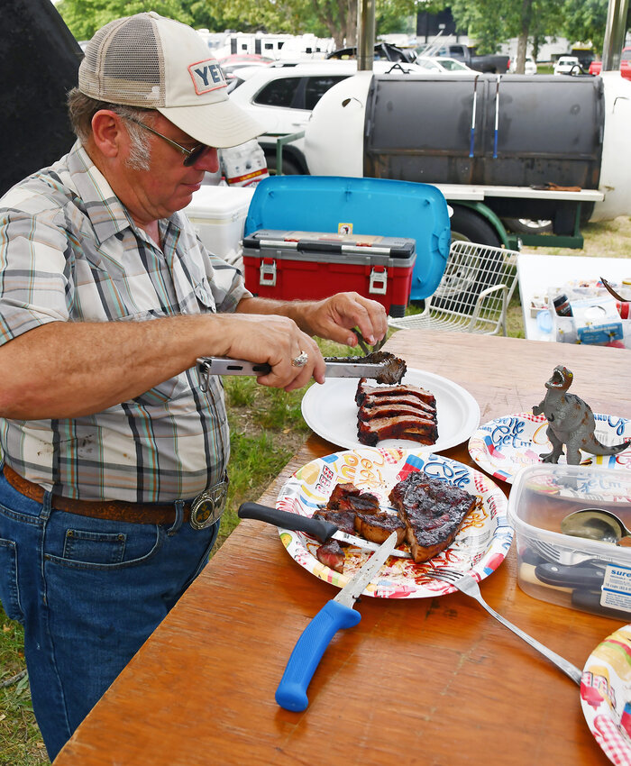 Ronnie Stockton prepares his ribs for the Kingsford Cook-Off at the Belle Fair. Stockton cooked with a toy dinosaur to highlight the fact he is the dinosaur in the group, the only cook to compete in all 40 years of the Kingsford Cook-Off.