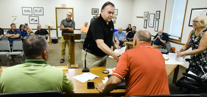 DAVID KELLY, director of Missouri State Parks, shakes hands Thursday morning with Southern District Gasconade County Commissioner Jerry Lairmore after signing an agreement for upkeep on the Rock Island Trail once sections are completed in the county. Ron Bentch, scope project manager for development of the Rock Island Trail (center) also visited with the commissioners and County Clerk Lesa Lietzow (far right).